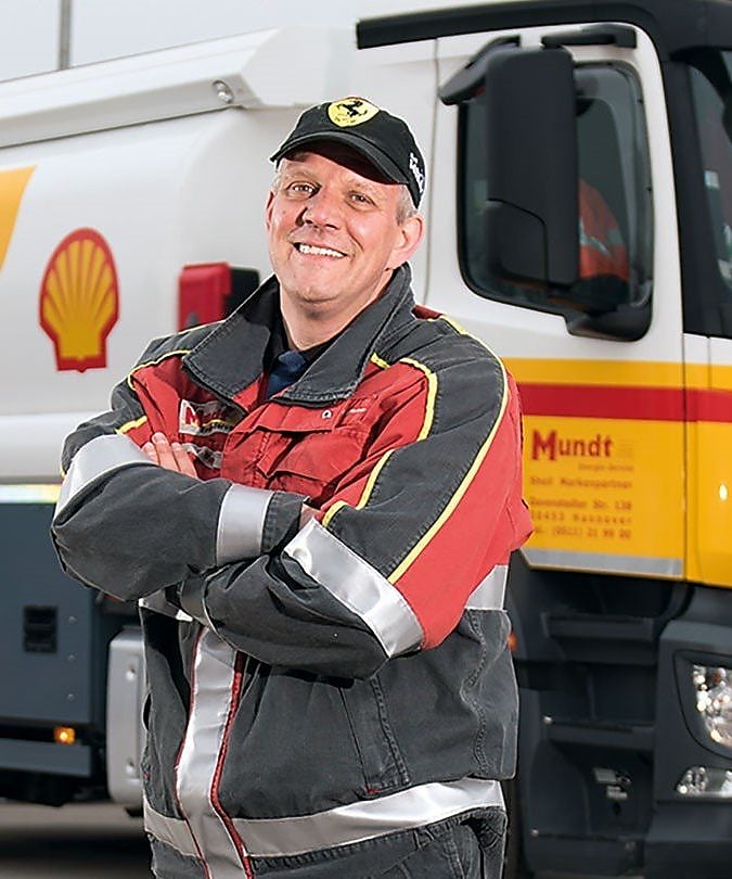 Tankwagenfahrer steht vor Shell Truck und lächelt