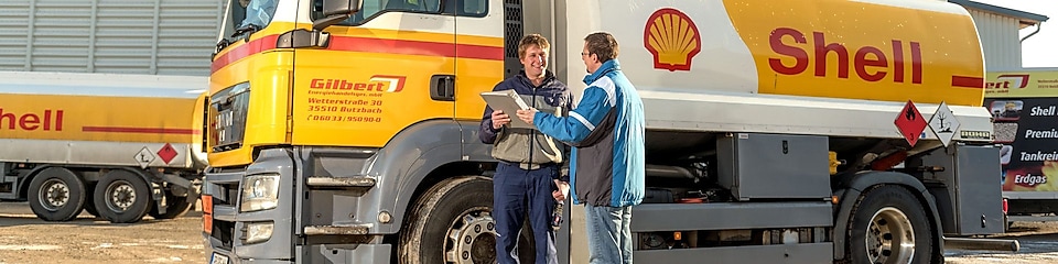 Zwei Mitarbeiter überprüfen Papiere neben Shell Tankwagen