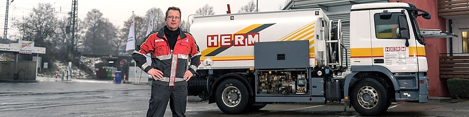 Herm GmbH Tankwagenfahrer steht neben Tankwagen
