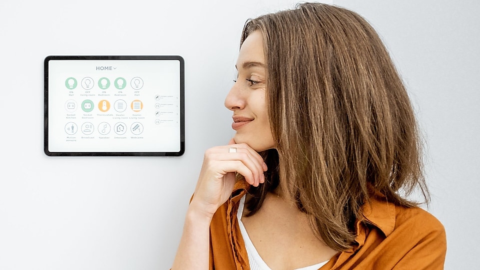 Frau schaut zu Smart Home Bildschirmoberfläche an der Wand