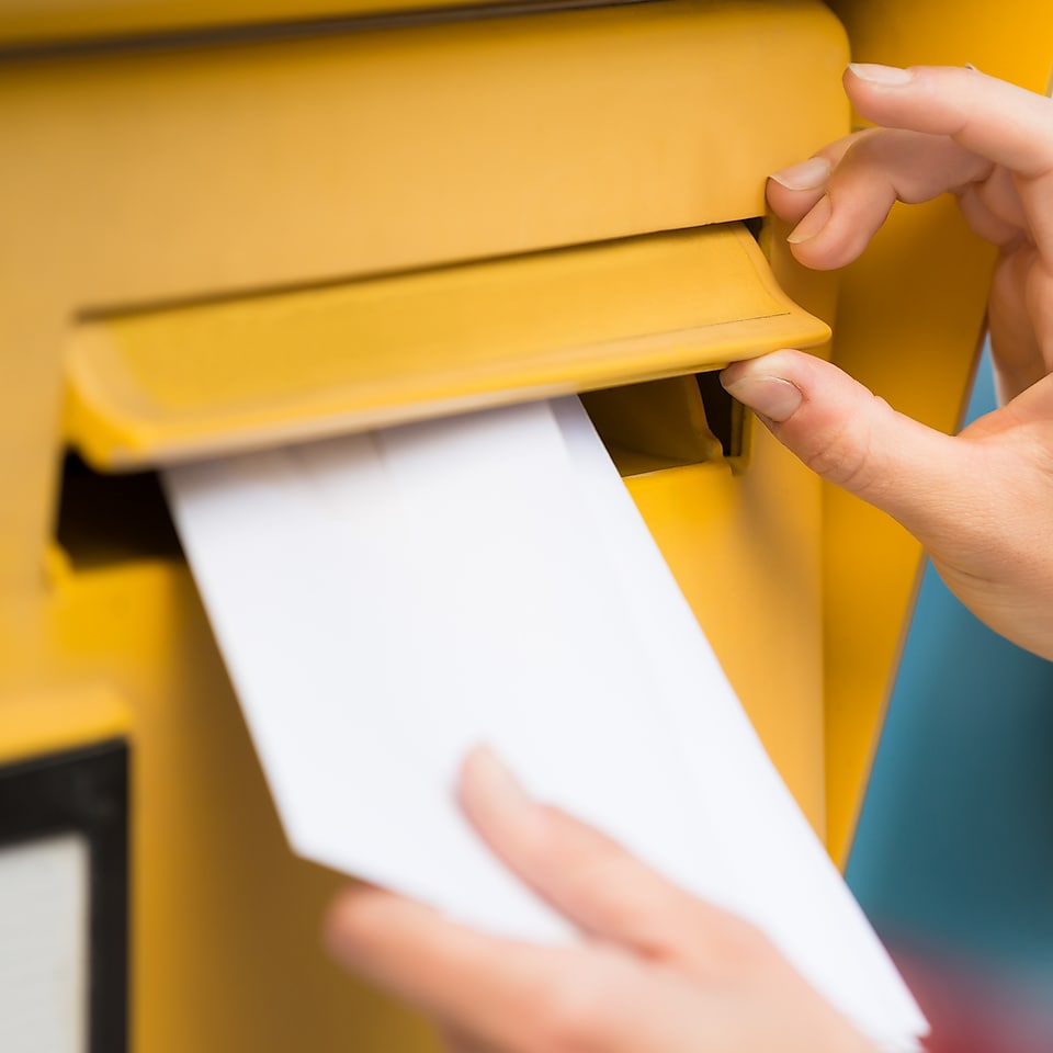 Hände werfen Brief in Briefkasten ein