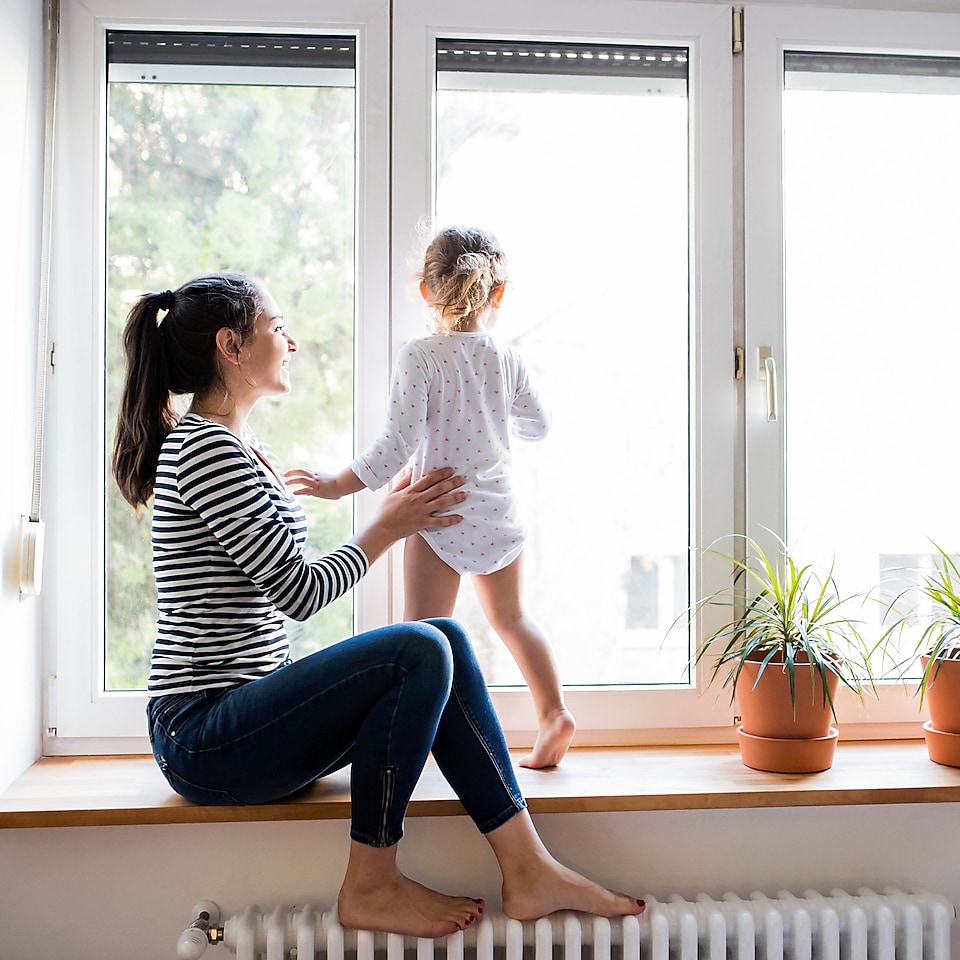 Frau mit kleinem Mädchen am Fenster