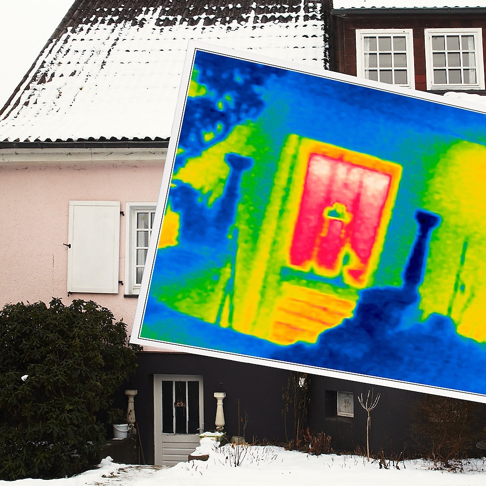 Thermoscan mit Haus im Hintergrund, mit Schnee bedecktes Dach